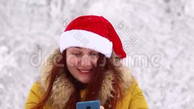 穿着<strong>保暖</strong>冬衣和圣诞<strong>帽</strong>的年轻女孩使用智能手机，体验快乐的情绪